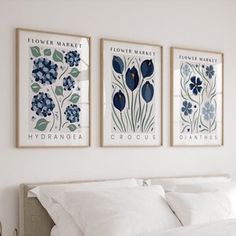 three blue and white flowers are hanging on the wall above a bed in a bedroom