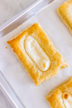 three pastries sitting on top of a white tray next to each other in plastic containers