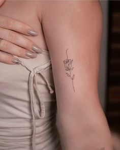 a woman's arm with a single rose tattoo on the left side of her arm