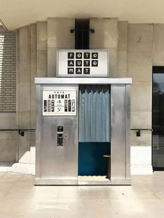 an atm machine sitting in front of a building next to a doorway with curtains on it