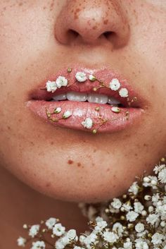 a woman with freckles on her lips and flowers in front of her face