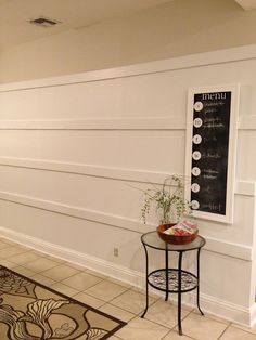 a small table with a potted plant on it in front of a chalkboard