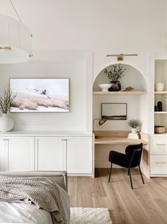 a bedroom with white walls and wooden flooring, built - in shelving units