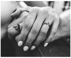 two people holding hands with tattoos on their fingers