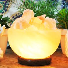 a bowl filled with yellow sugar sitting on top of a wooden table next to potted plants