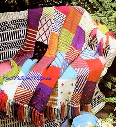 a colorful blanket sitting on top of a white bench next to a flower vase and potted plant