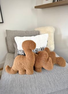 two stuffed animals sitting on top of a bed next to a pillow and pillows in a room