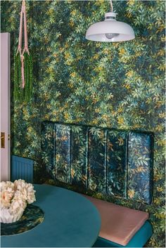 a dining room with green wallpaper and blue chairs, white flowers on the table