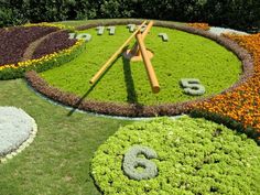 a clock made out of flowers and grass with numbers in the middle on it's sides