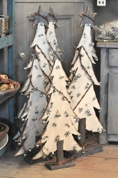 two wooden christmas trees sitting next to each other on top of a table in front of a cabinet