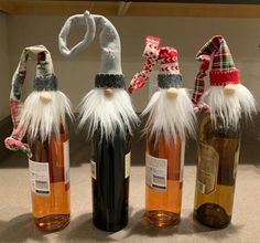 three wine bottles with santa hats on them and one has a bottle opener in the shape of an elf's head