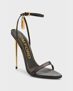 "Find TOM FORD Lock Stiletto Sandals on Editorialist. TOM FORD sandal in shiny goatskin leather. Signature hanging padlock and key charm. 4.3\" metallic stiletto heel. Pointed open toe. Single band upper. Adjustable halter ankle wrap. Leather outsole. Made in Italy." Tom Ford Sandals, Tom Ford High Heels, Tom Ford Shoes Women, Tom Ford Lock Heels, Luxury Leather T-strap Sandals With Heel Strap, Gold Tom Ford Heels, Tom Ford Heels Stilettos, Tom Ford Heels, Luxury Black T-strap Sandals With Single Toe Strap