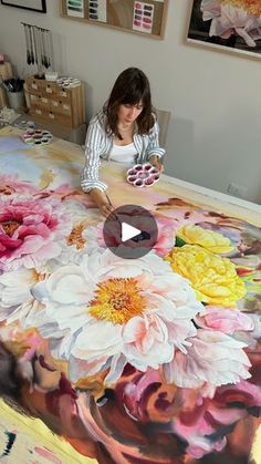 a woman is painting flowers on a large table