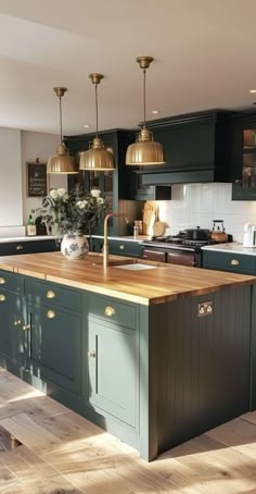 a large kitchen with an island in the middle of it and gold pendant lights hanging from the ceiling