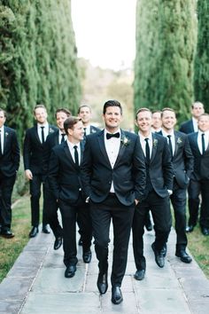 a group of men in tuxedos walking down a sidewalk