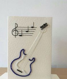 a white card with a stringed instrument and musical notes on the front, sitting on top of a wooden table