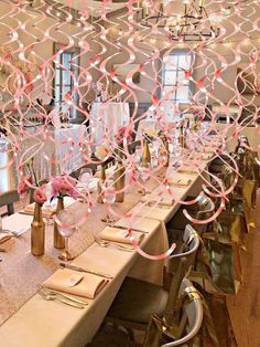 a long table is set with place settings and pink flowers in vases on the tables