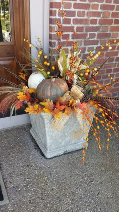 a potted planter filled with fall flowers and pumpkins