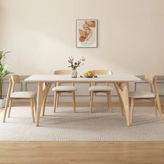 a dining room table with four chairs and a potted plant in the corner next to it