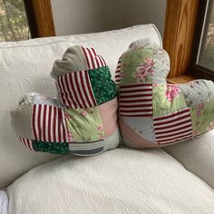 two pillows are sitting on the back of a white couch in front of a window