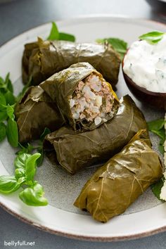 stuffed grape leaves on a plate with cream cheese and spinach garnishes