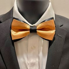 The item is a pretied adjustable antique gold bow tie framed and black satin.  The item would be a great accessory to provide that black and antique gold accent to an attire for a special occasion. Gold Bow Suit And Tie Accessories As Gift, Classic Gold Suit And Tie Accessories With Bow Tie, Gold Suit And Tie Accessories With Bow For Gift, Black Satin Tuxedo For Party, Classic Gold Suit And Tie Accessories With Satin Bow, Classic Gold Suit Accessories With Satin Bow, Gold Adjustable Suit And Tie Accessories For Party, Adjustable Gold Bow Tie For Black Tie Events, Fitted Gold Bow Tie And Suit Accessories