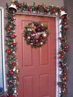 a red door decorated with christmas wreaths and ornaments