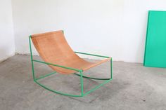 a wooden chair sitting on top of a cement floor next to a green cabinet and door