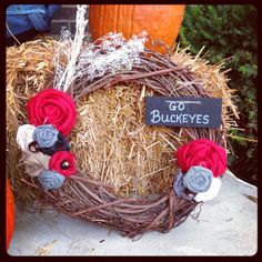 a wreath made out of hay with red and gray flowers on it that says go bukeyes