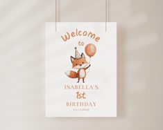 a welcome sign hanging on a wall with a little fox holding a balloon in it's mouth