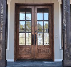 two wooden doors with glass on the front of a house in an open country style