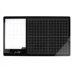 a black cutting board with a white grid pattern on the front and back side, sitting next to a ruler