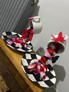 two black and white plates with flowers on them sitting on a table next to a wall