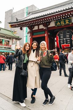 three women taking a selfie in front of a building with chinese characters on it