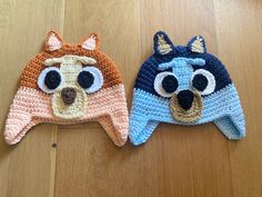 two crocheted hats with eyes and ears on top of a wooden floor next to each other