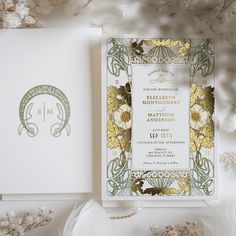 the wedding stationery is laid out on top of white paper and gold foil flowers