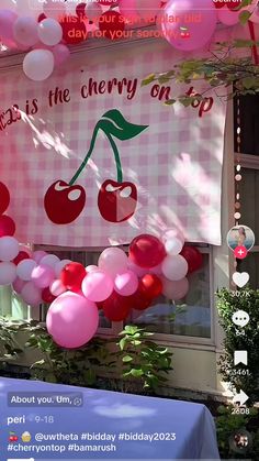 balloons and streamers are hanging from the side of a building in front of a cherry themed banner