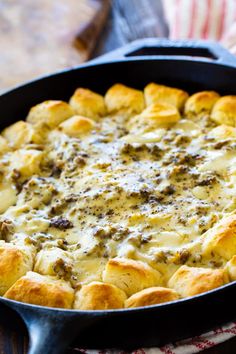 a casserole dish with cheese and meat in it sitting on a wooden table