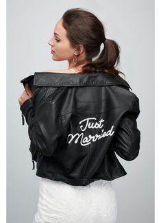 a woman wearing a black leather jacket with just married written on the back in white