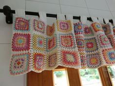 three crocheted squares are hanging on the curtain rod