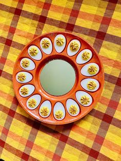 an orange and white plate sitting on top of a checkered table cloth with yellow flowers