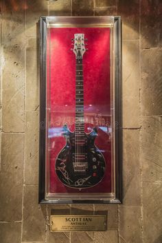 an electric guitar on display in a glass case with a plaque underneath it stock photos