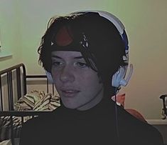 a young man wearing headphones in his bedroom