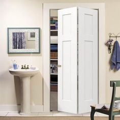 an open door in a bathroom next to a sink and chair with towels hanging on the wall