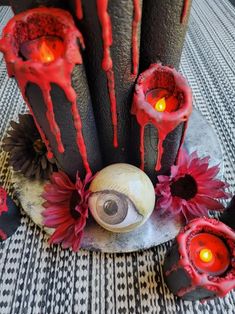 an arrangement of candles and fake flowers on a table with blood dripping down the top