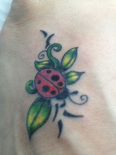 a ladybug tattoo on the foot of a woman