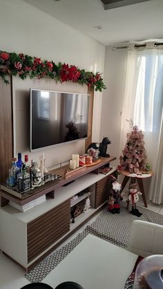 a living room with christmas decorations and a flat screen tv on top of a entertainment center