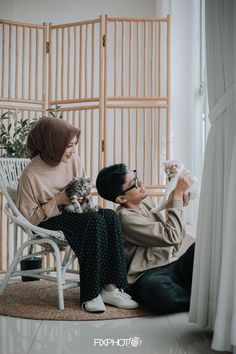 a man and woman sitting on a chair with a cat