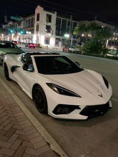 a white sports car is parked on the side of the road