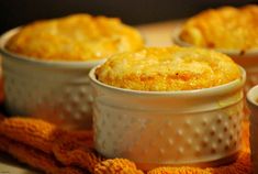 three small white dishes filled with food on top of a table